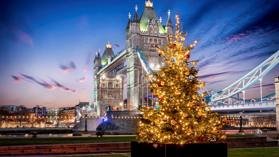 Die Tower Bridge in London bei Nacht mit einem festlich beleuchtetem Weihnachtsbaum davor, Großbritannien