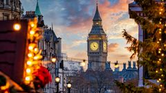 Beautiful sunset view of the Big Ben Clocktower in London, England, with the fairy lights from the Trafalgar Square Christmas market in front