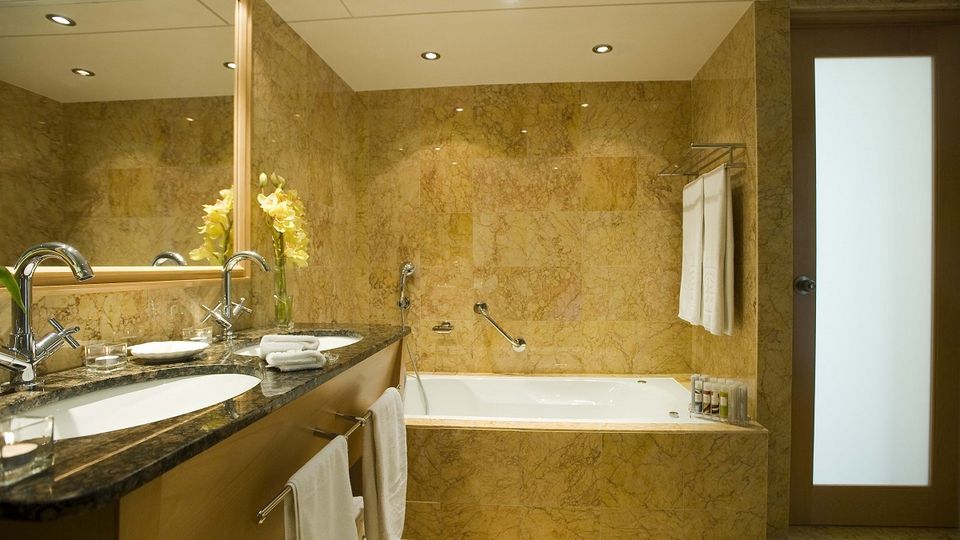 Elegantes Badezimmer mit Marmorfliesen, Doppelwaschbecken und großer Badewanne.