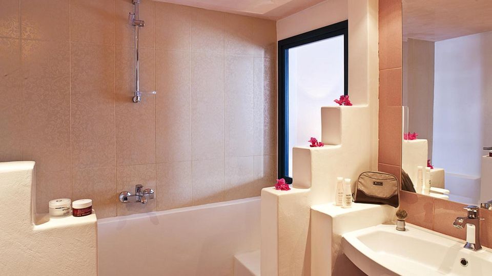 Helles Badezimmer mit Badewanne, großem Spiegel und liebevollen Details wie Dekoblumen – für entspannte Wohlfühlmomente.