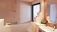 Helles Badezimmer mit Badewanne, großem Spiegel und liebevollen Details wie Dekoblumen – für entspannte Wohlfühlmomente.