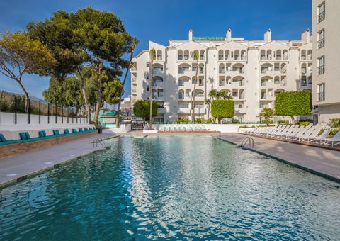 Außenansicht des Occidental Puerto Banús Hotels mit großem Swimmingpool, Sonnenliegen und mediterraner Gartenanlage – ideal für entspannte Urlaubstage in der Sonne.