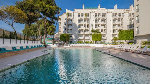 Außenansicht des Occidental Puerto Banús Hotels mit großem Swimmingpool, Sonnenliegen und mediterraner Gartenanlage – ideal für entspannte Urlaubstage in der Sonne.