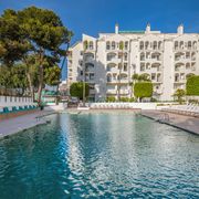Außenansicht des Occidental Puerto Banús Hotels mit großem Swimmingpool, Sonnenliegen und mediterraner Gartenanlage – ideal für entspannte Urlaubstage in der Sonne.