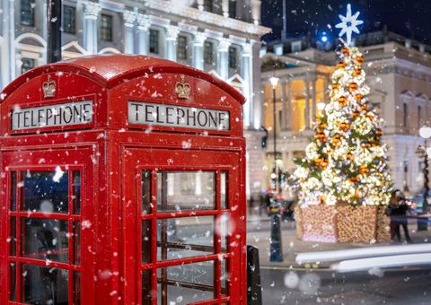 Rote Telefonzelle in London vor einem beleuchtetem Weihnachtsbau