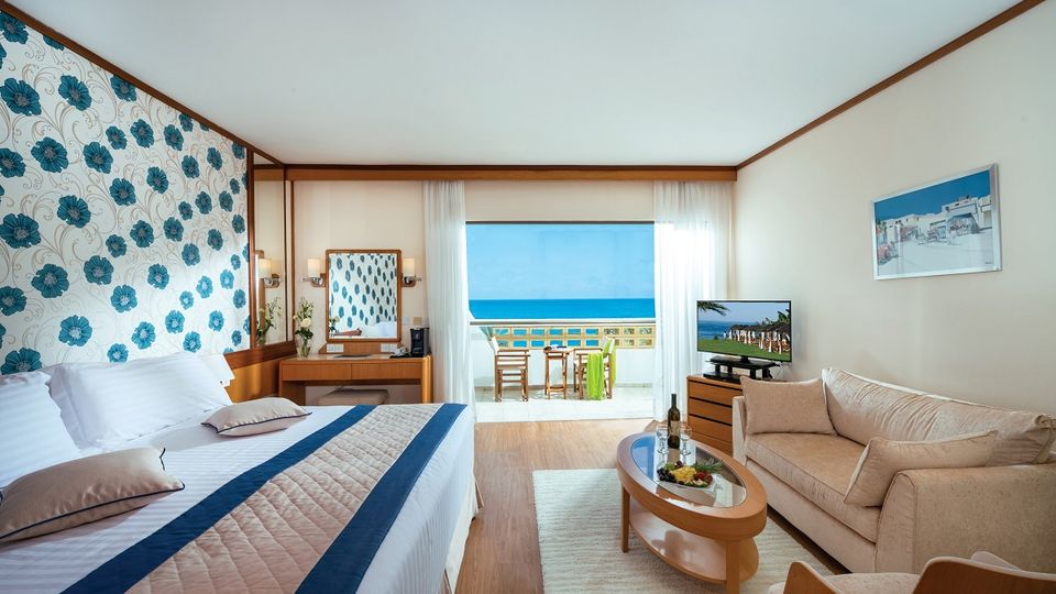 Modern eingerichtetes Zimmer mit gemütlicher Sitzecke und herrlichem Ausblick auf das türkisblaue Meer.
