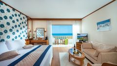 Modern eingerichtetes Zimmer mit gemütlicher Sitzecke und herrlichem Ausblick auf das türkisblaue Meer.