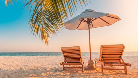 Liege mit Sonnenschirm am Strand bei einem Badeurlaub mit sz-Reisen