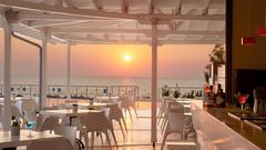 Stilvolle Hotelbar mit weißem Interieur und traumhaftem Blick auf das Meer – ideal, um den Sonnenuntergang bei einem Cocktail in entspannter Atmosphäre zu genießen.