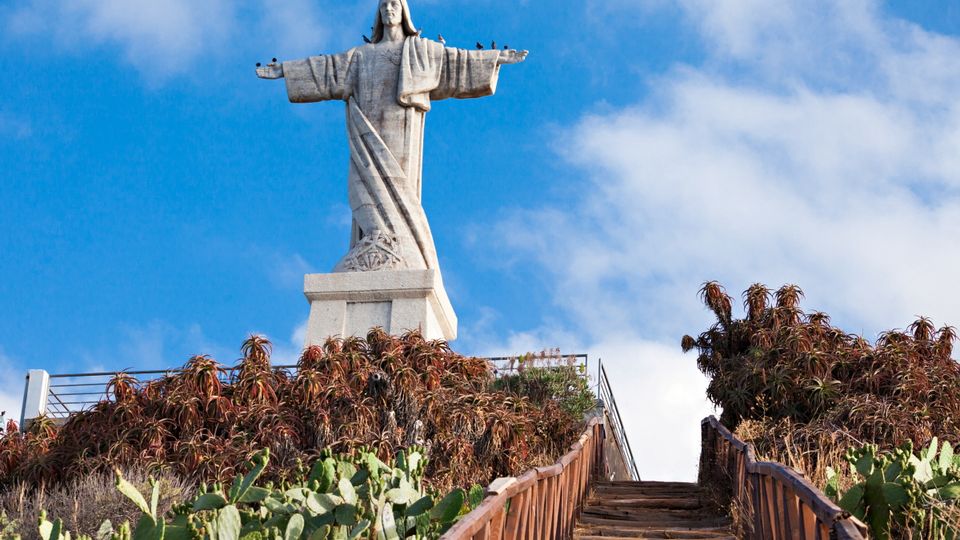 Die Christo-Rei-Statue auf Madeira: Eine eindrucksvolle Christusstatue mit ausgebreiteten Armen, stehend auf einem Felsvorsprung mit Blick auf den Atlantischen Ozean.