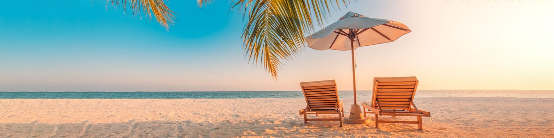Liege mit Sonnenschirm am Strand bei einem Badeurlaub mit sz-Reisen