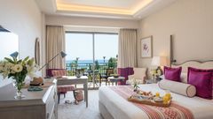 Helles, stilvoll eingerichtetes Zimmer mit Meerblick und liebevoll angerichtetem Frühstück auf dem Bett.