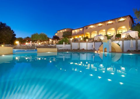 Stimmungsvoll beleuchteter Hotelpool in der Dämmerung mit Wasserrutsche, gemütlichen Liegeinseln und elegantem Hotelgebäude im Hintergrund – ideal für entspannte Abende in mediterranem Ambiente.