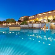 Stimmungsvoll beleuchteter Hotelpool in der Dämmerung mit Wasserrutsche, gemütlichen Liegeinseln und elegantem Hotelgebäude im Hintergrund – ideal für entspannte Abende in mediterranem Ambiente.