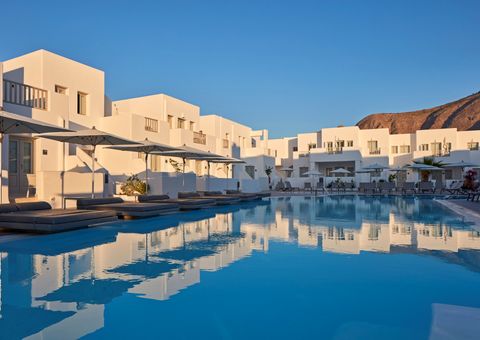 Modernes Hotel im kubischen Stil mit weiß getünchten Fassaden, großzügigem Poolbereich und bequemen Liegen unter Sonnenschirmen – ideal zum Entspannen in der Abendsonne.