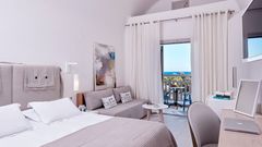 Helles, modern eingerichtetes Zimmer mit gemütlichem Bett, Sitzecke und Balkon – mit traumhaftem Blick auf das Meer und Palmen.