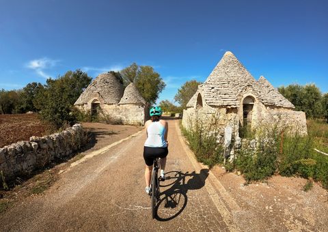 Radfahrerin bei Trulli-Häusern in Apulien