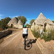 Radfahrerin bei Trulli-Häusern in Apulien