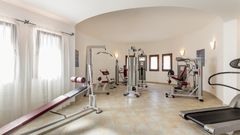 Heller Fitnessraum mit mehreren modernen Kraftgeräten, Hantelbank und Laufband – ideal für ein ausgiebiges Workout im Urlaub.