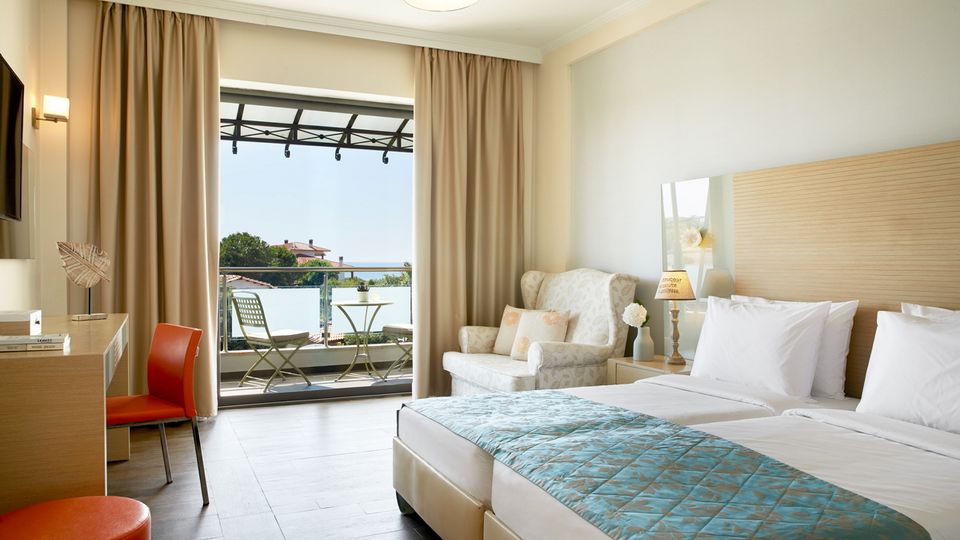 Stilvolles Doppelzimmer mit Balkon und gemütlicher Sitzecke – ideal für erholsame Urlaubstage.