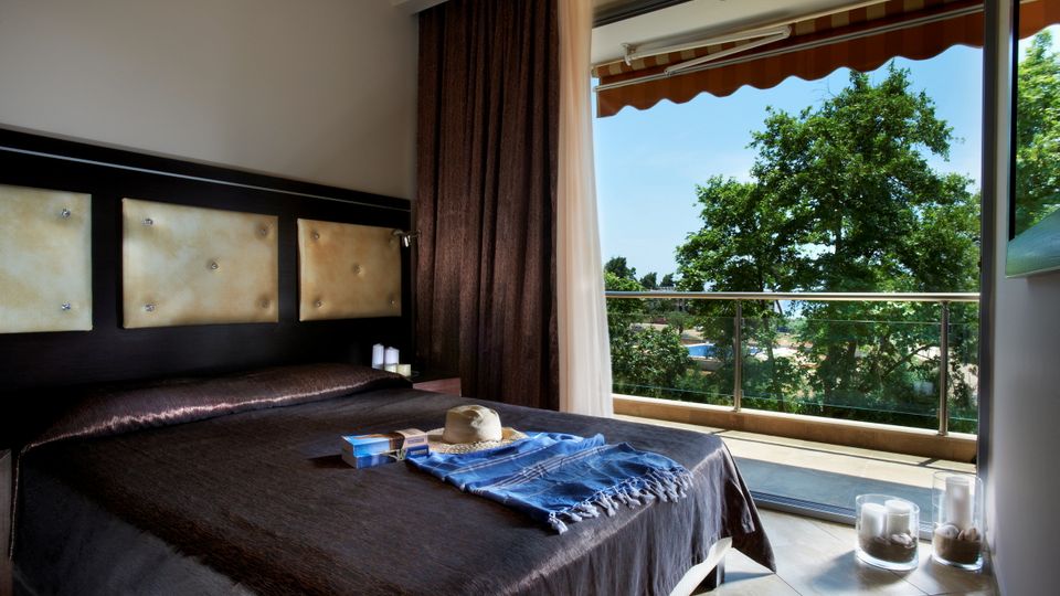 Komfortables Doppelzimmer mit elegantem Design und Zugang zum Balkon – genießen Sie entspannte Stunden mit Blick ins Grüne.